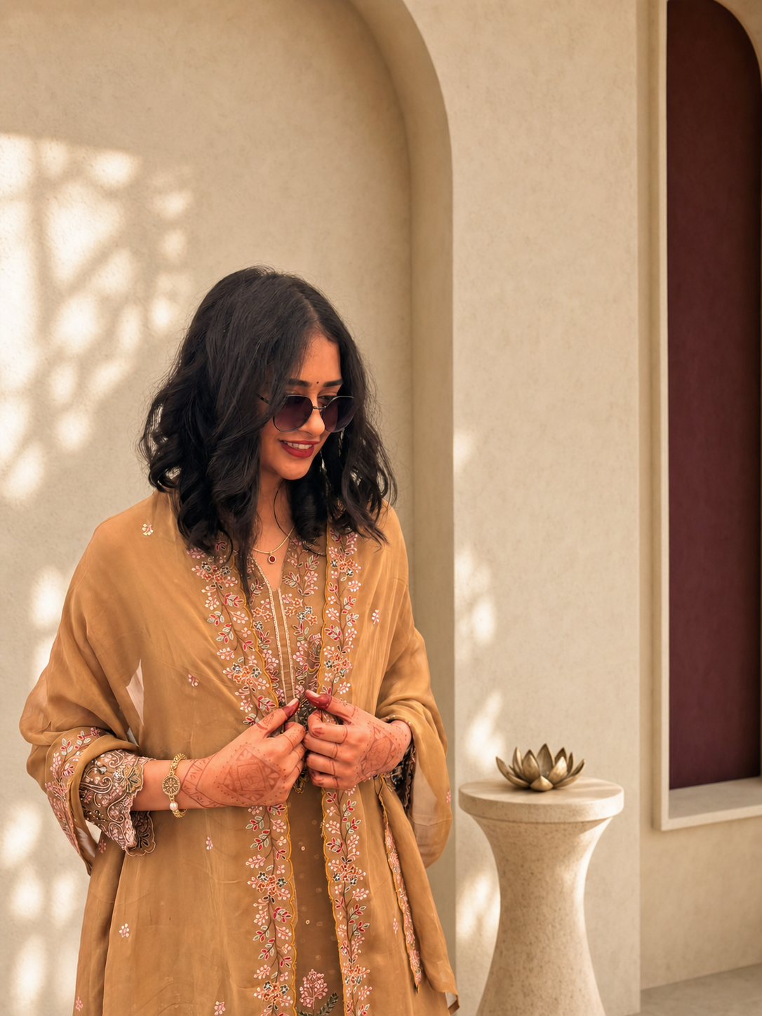 Miss Pooja in a warm embroidered outfit wearing delicate gold jewellery